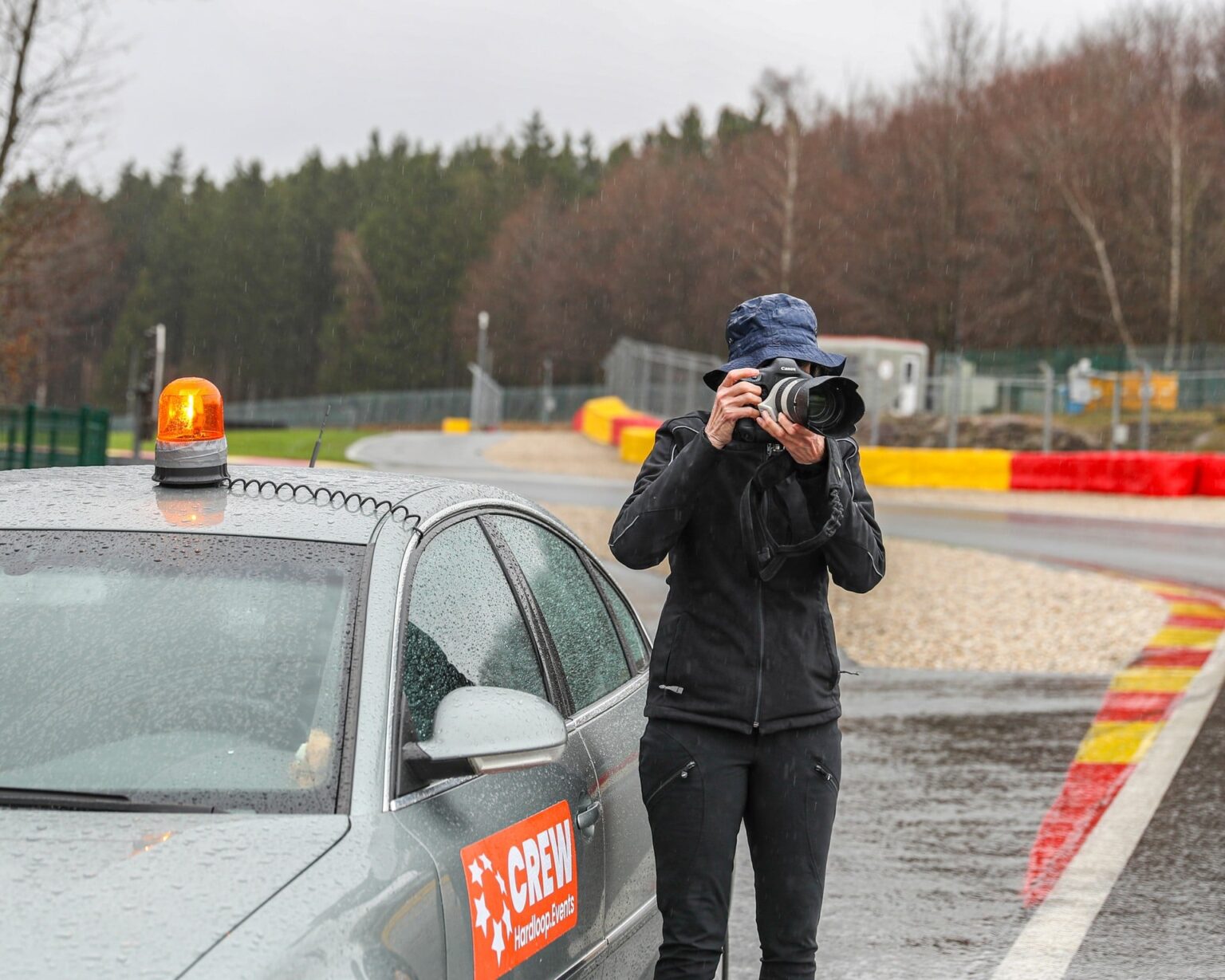 Fotograaf naast naast een auto op het Formule 1-circuit tijdens een hardloopevenement.